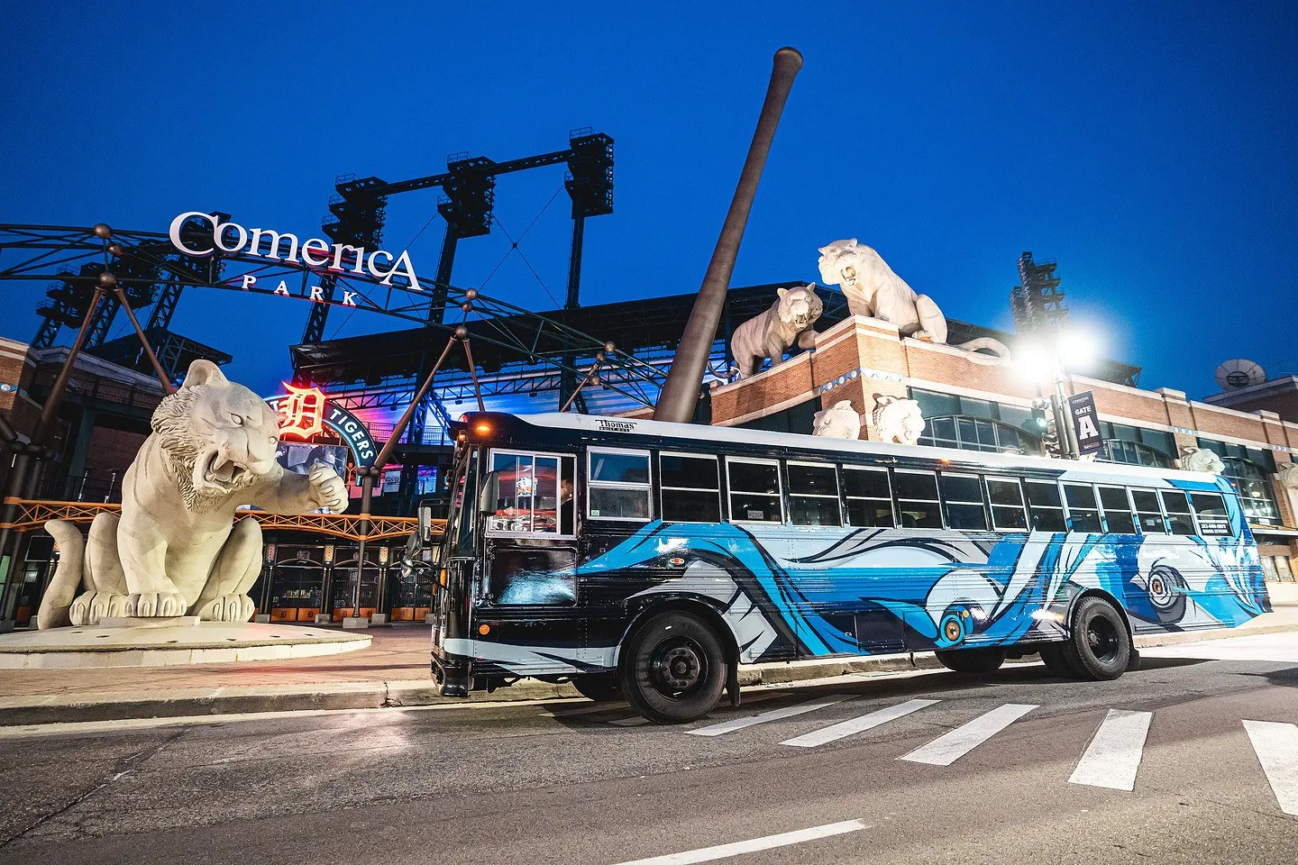 Belle the Art Bus parked beneath the tiger statues at Comerica Park on game night
