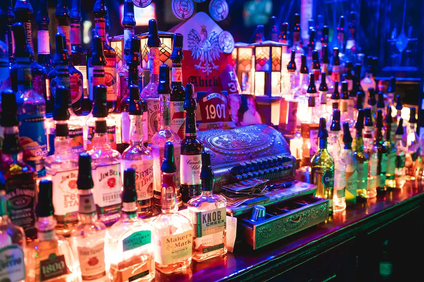 A glowing back bar crowded with bottles at Abick's, pouring since 1907
