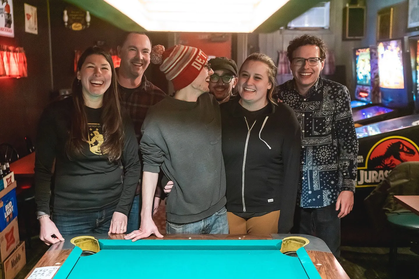 A group of guests laughing around a pool table at a historic Detroit bar