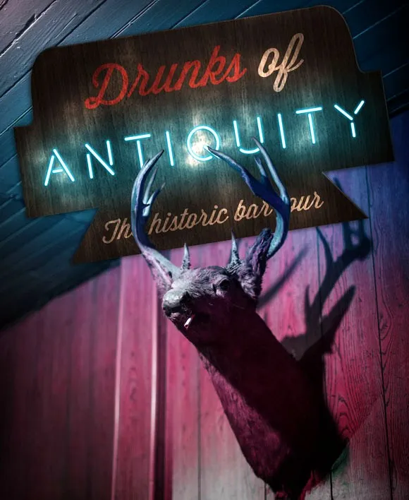 The Drunks of Antiquity sign — 'The historic bar tour' — beside a taxidermy deer head
