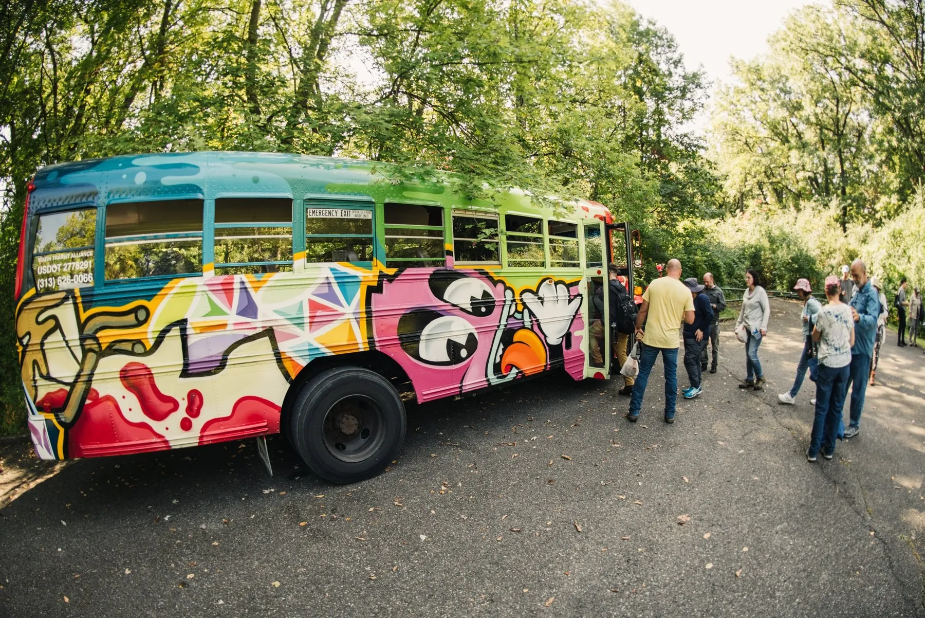 A group gathered beside the pink graffiti-painted bus before a foraging tour