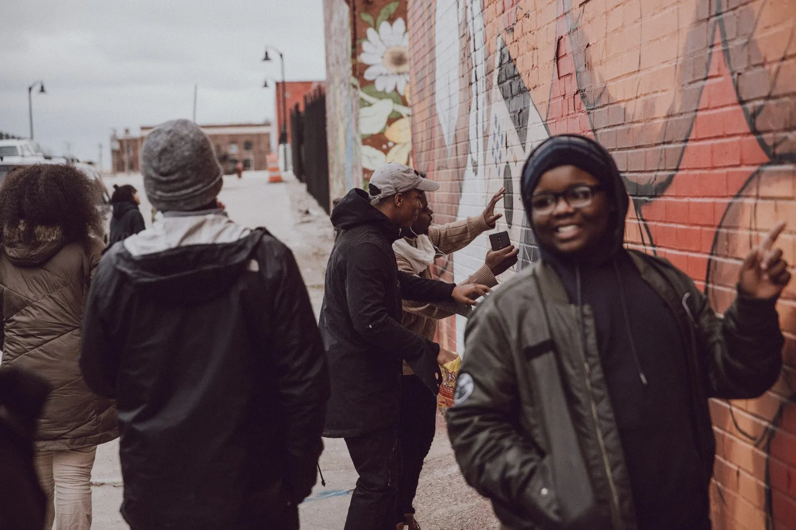 A student grinning in front of a Detroit mural with classmates
