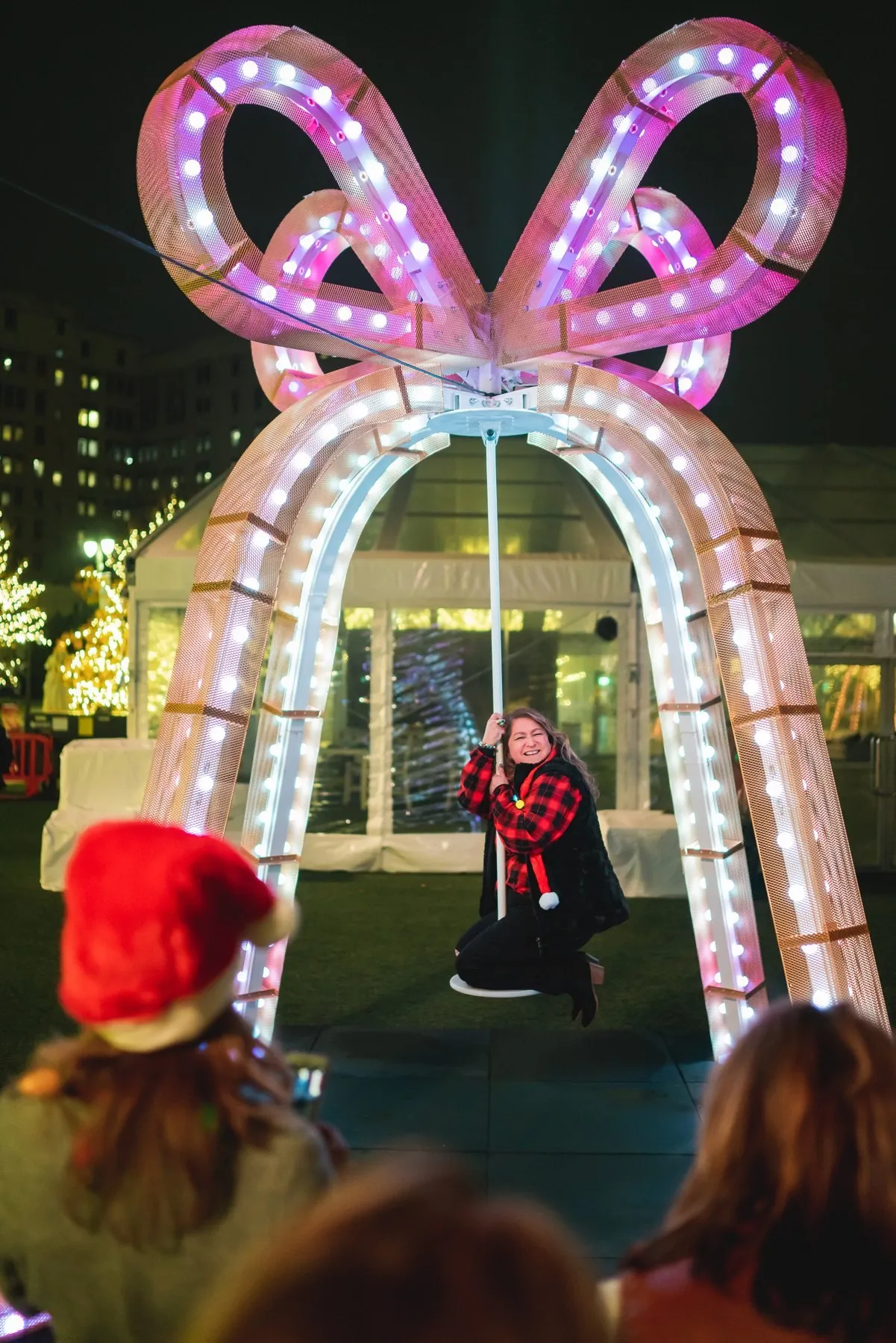 A guest swinging under a glowing candy-cane bow archway