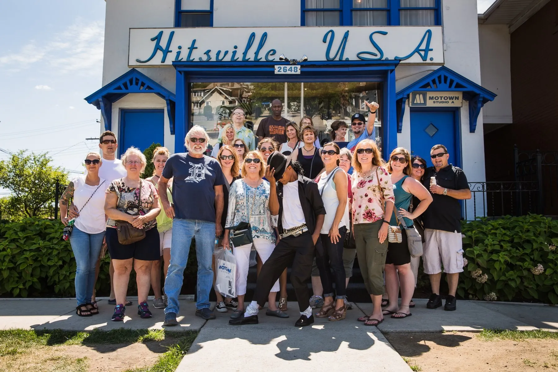 A big group posing together outside Hitsville U.S.A. on a Motown outing