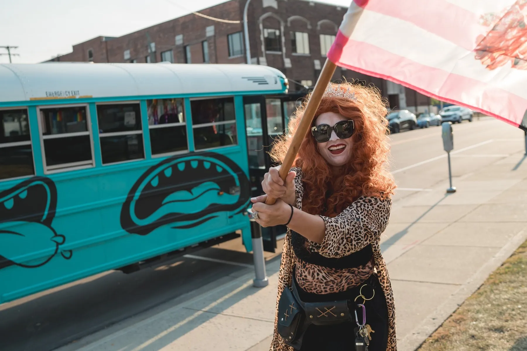 A fan waving a flag beside the teal Art Bus before the festival