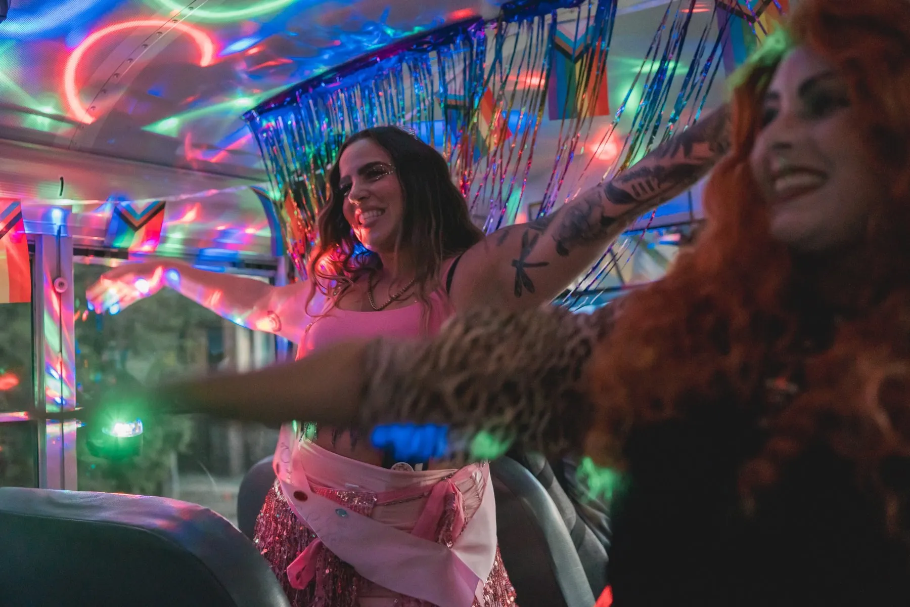 Riders dancing on the bus under colored lights at night