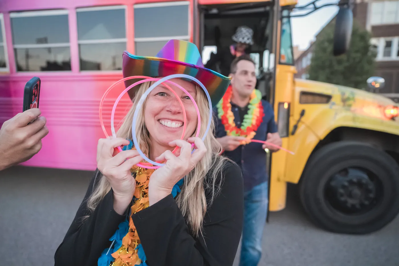 A smiling guest in a glowing cowboy hat between two painted buses
