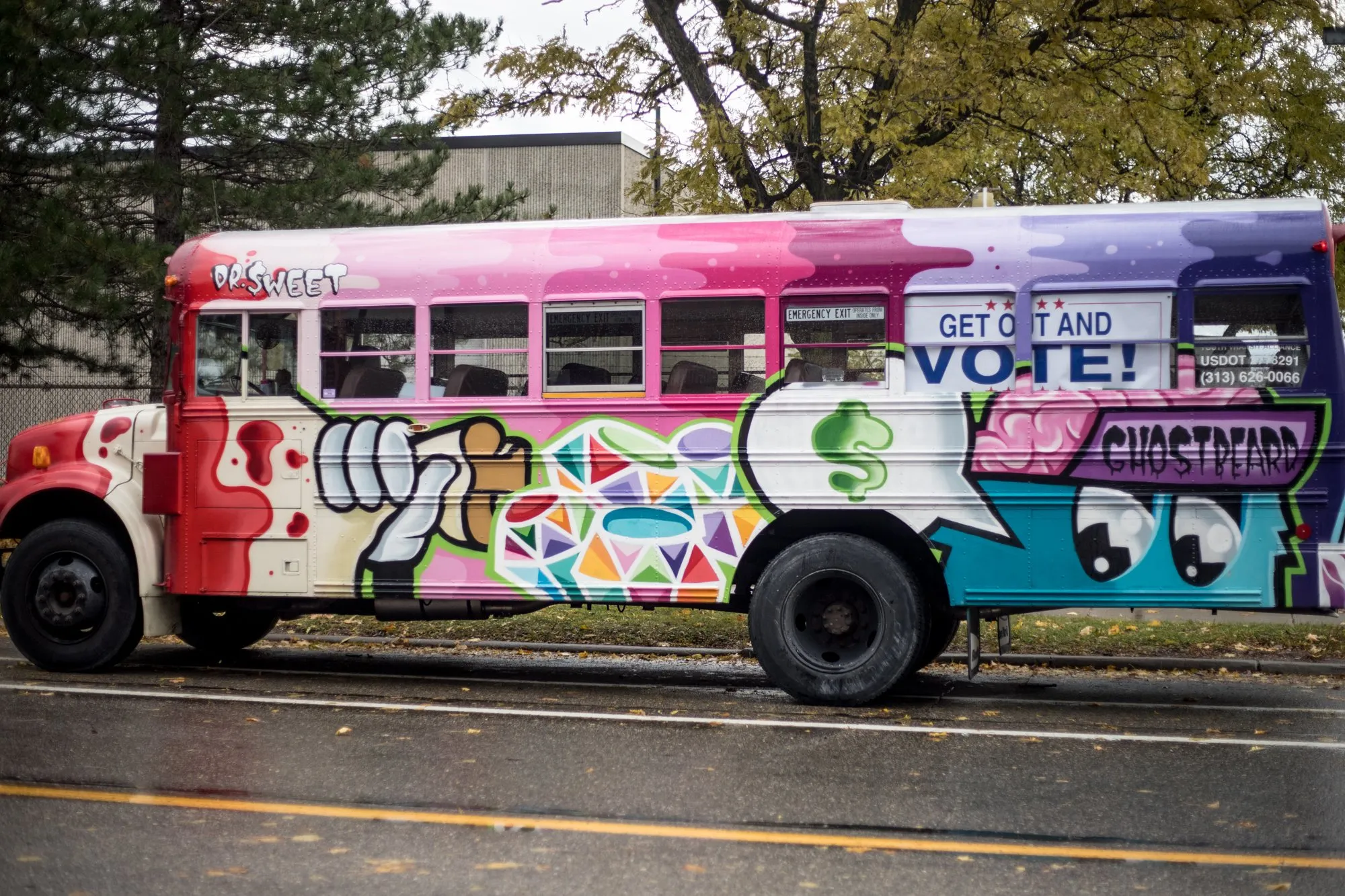 A hand-painted Detroit Bus Company bus with GET OUT AND VOTE painted across its side, rolling to the polls