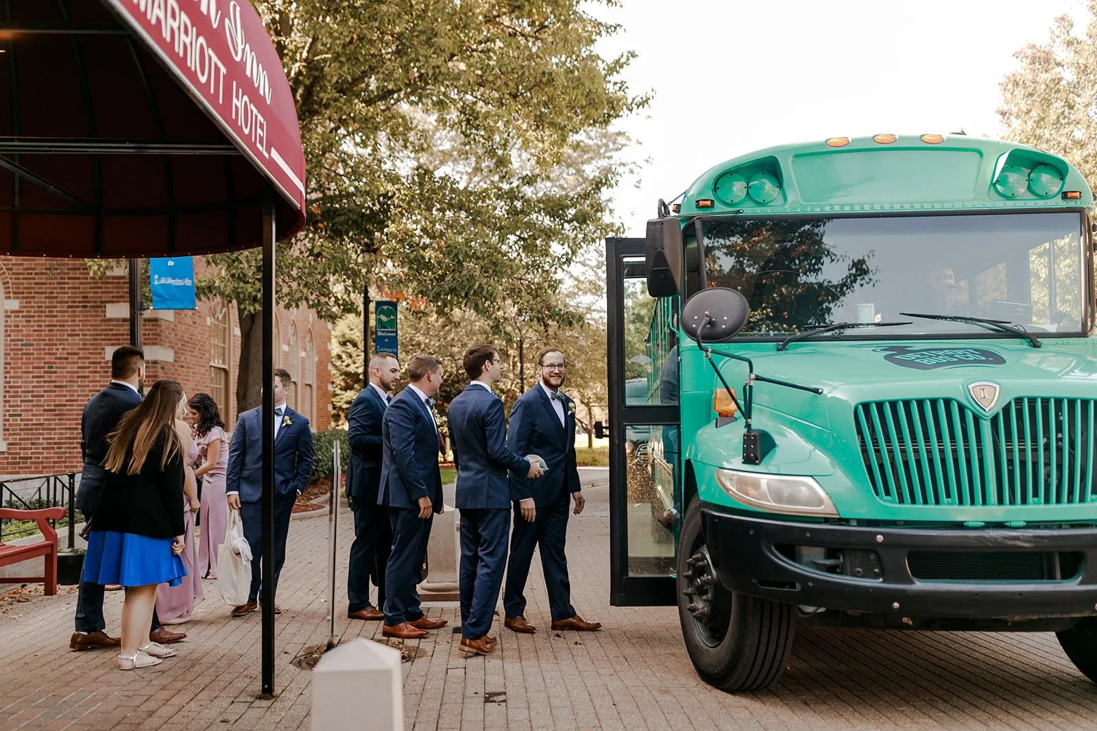 A wedding party boarding the teal Art Bus outside the hotel