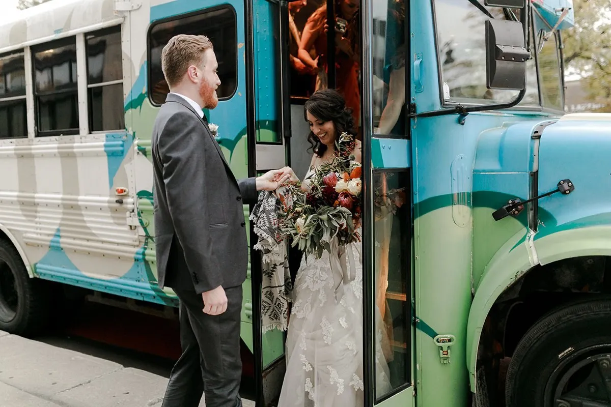 The groom meeting the bride as she steps off the painted bus