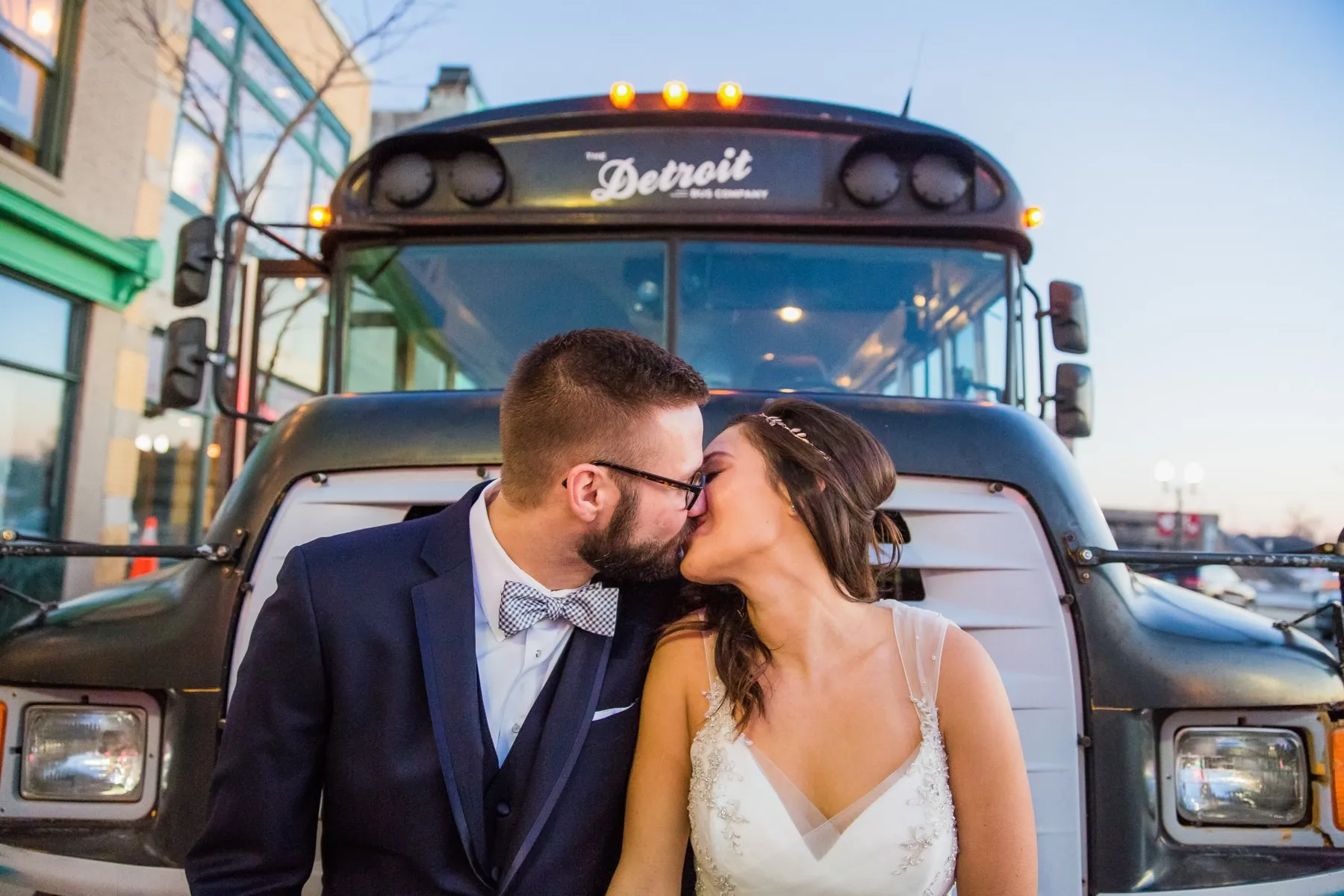 A couple kissing in front of the Detroit lettering on the bus grille