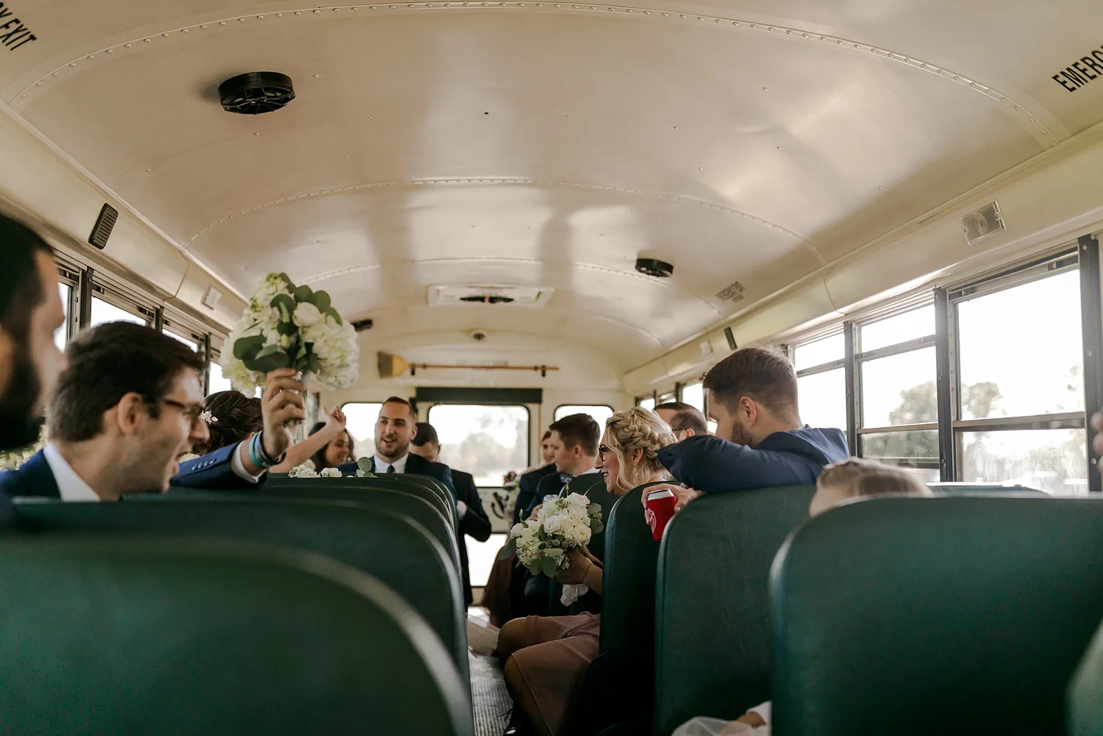 A wedding party riding the bus with bouquets in hand